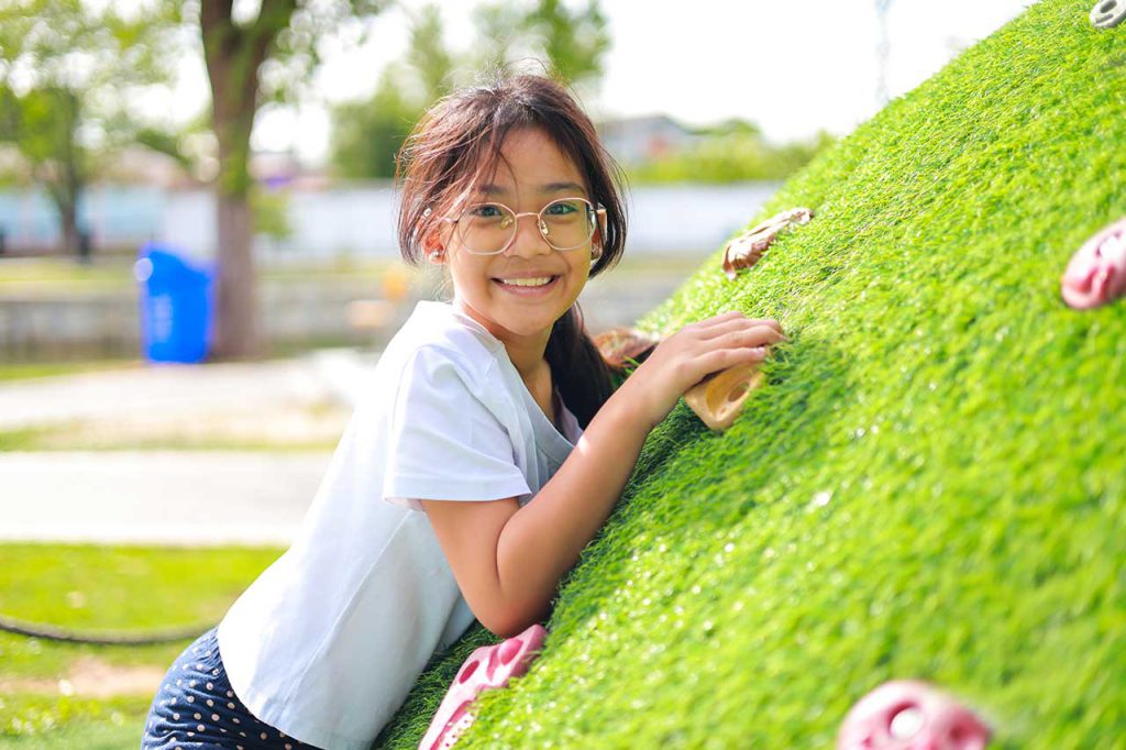 the girl leans on a green artificial hillside
