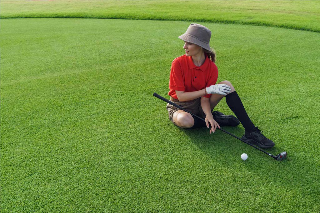 woman sits on an artificial golf course