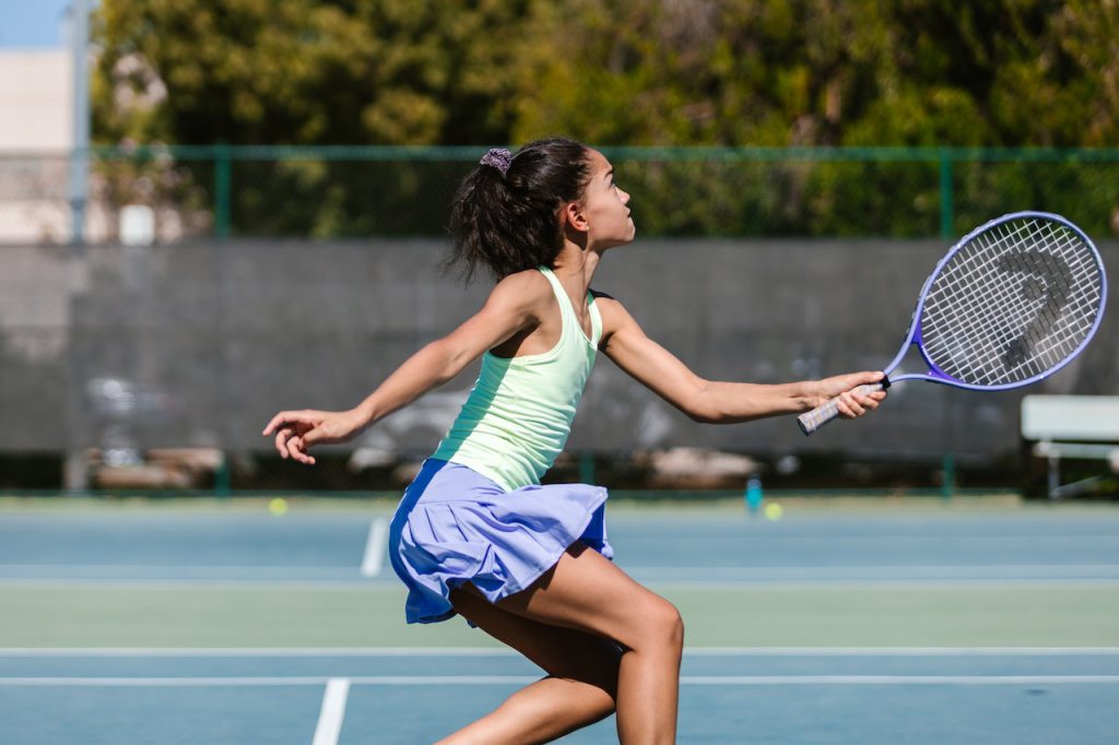 young girl plays tennis